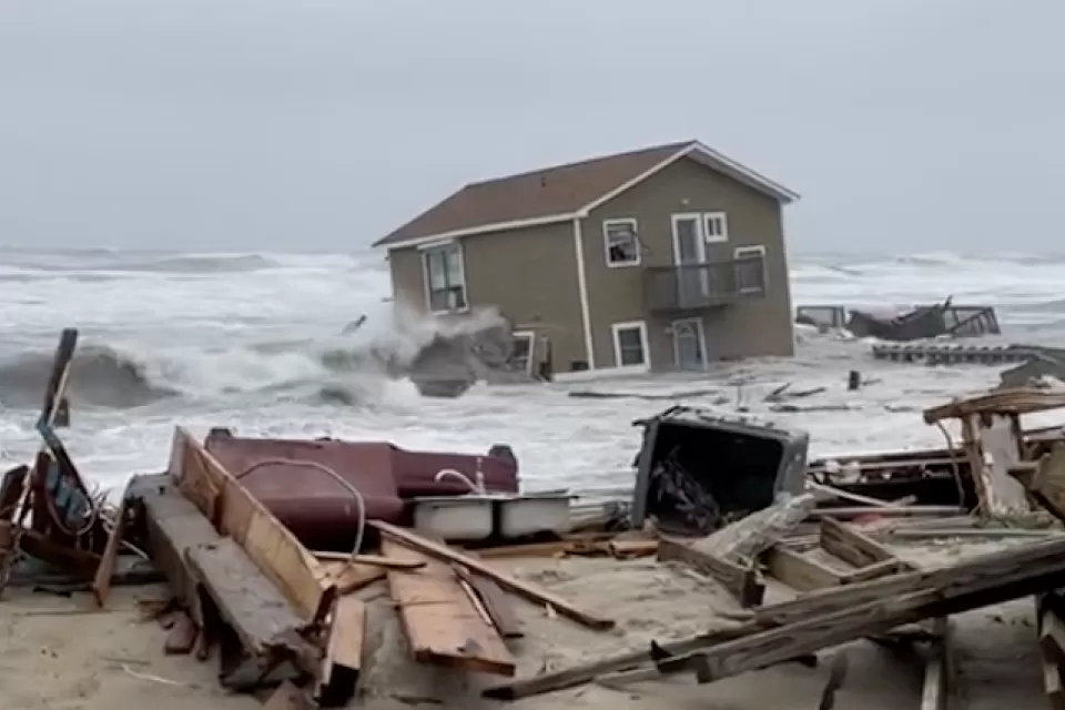 A house has been swept into the Atlantic Ocean by high tides, leaving ruins in onshore as the house appears half submerged by water,